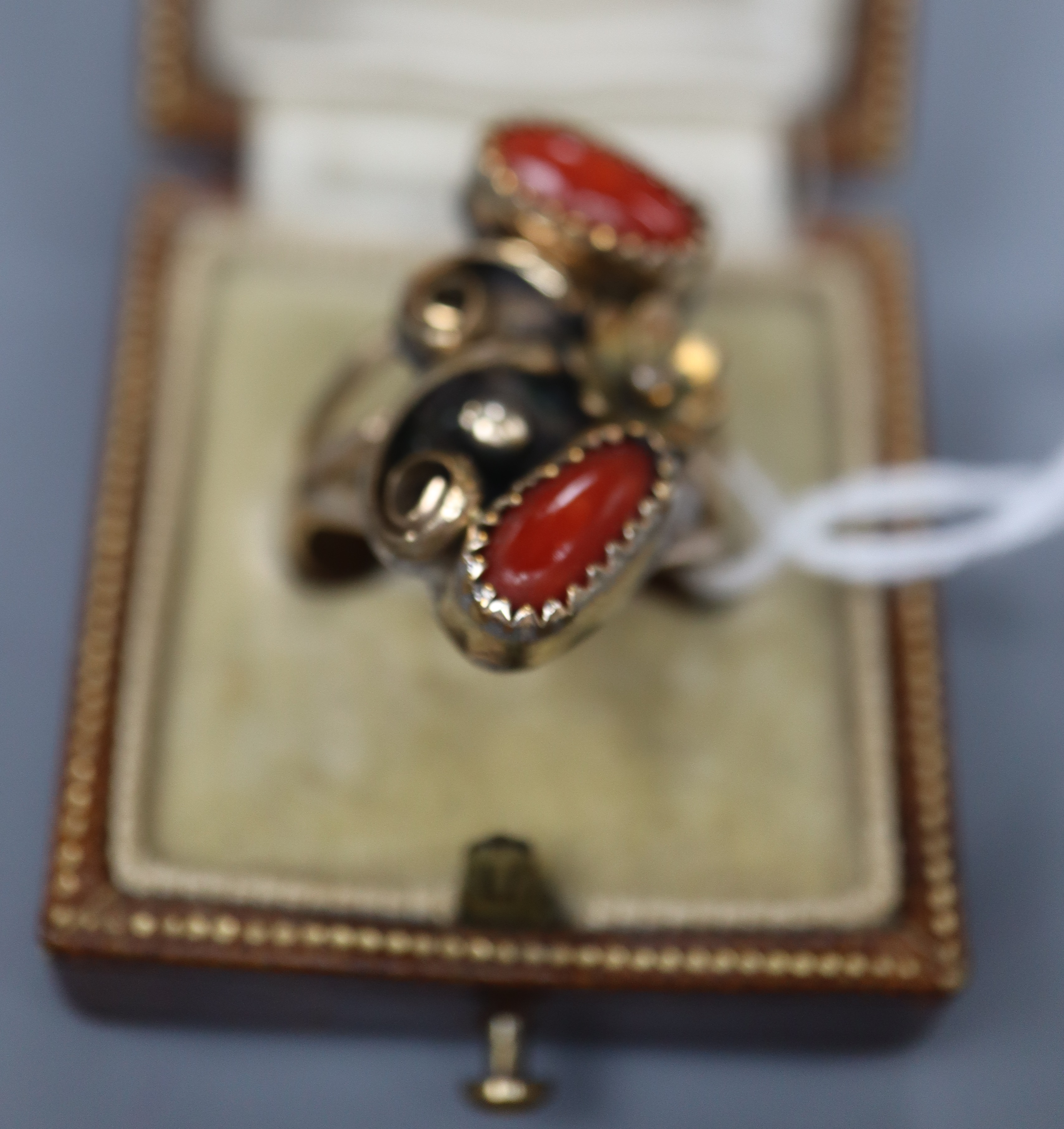 An early 20th century Arts & Crafts yellow and white metal and two stone cabochon coral set triple shank dress ring, size O,